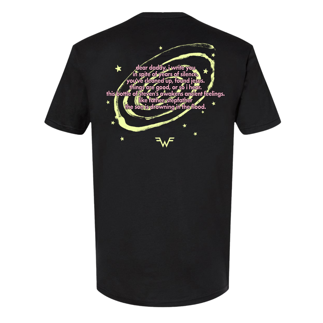 Black short-sleeved t-shirt featuring a glowing yellow circular design with stars and pink text, centered around the wonder woman logo.