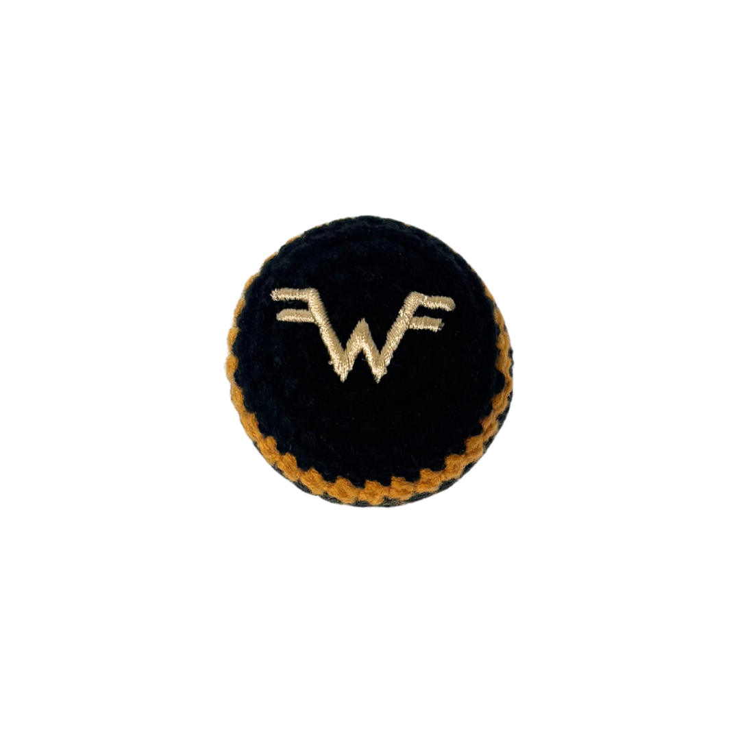 Black circular button with embroidered gold wf logo and stitched border on black and gold striped hacky sack