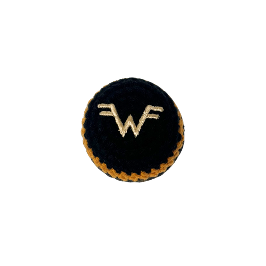 Black circular button with embroidered gold wf logo and stitched border on black and gold striped hacky sack