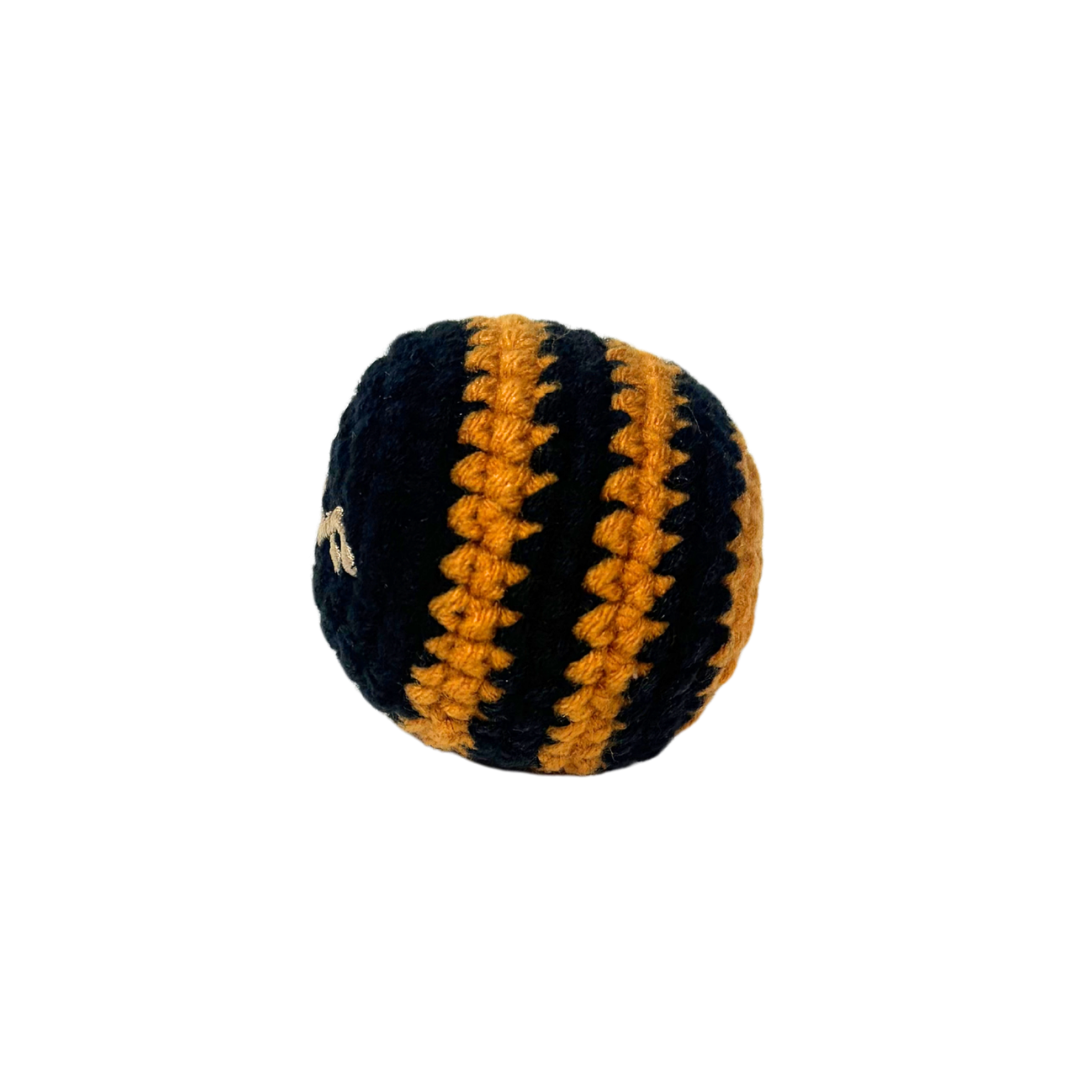 A handcrafted round crochet hacky sack with bold black and gold striped textured knitted surface